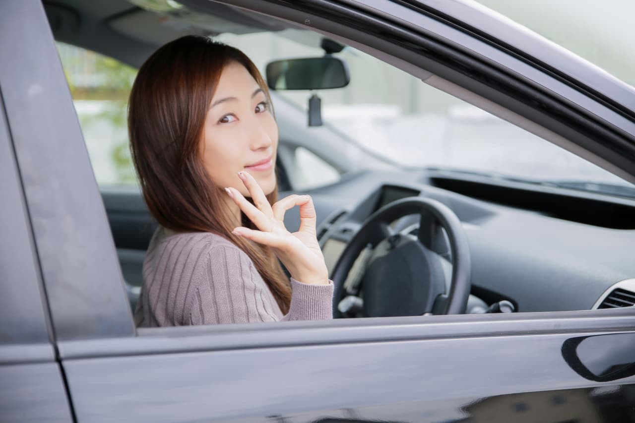 車からOKサインを出している女性